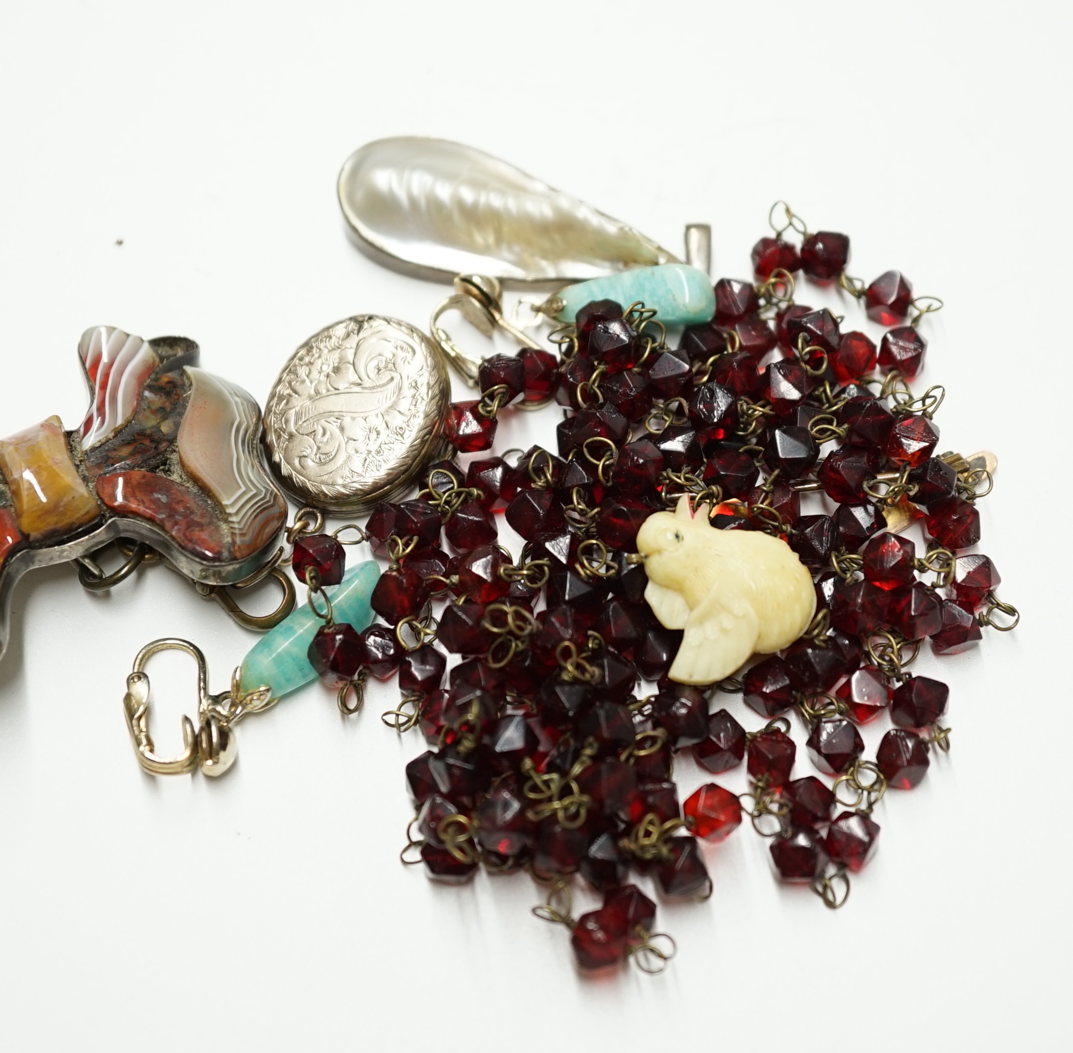 A late Victorian engraved gold plated and black enamel set oval mourning locket, suspended from a white metal and Scottish hardstone set ribbon bow brooch, overall 88mm, together with six other items including an Indian?